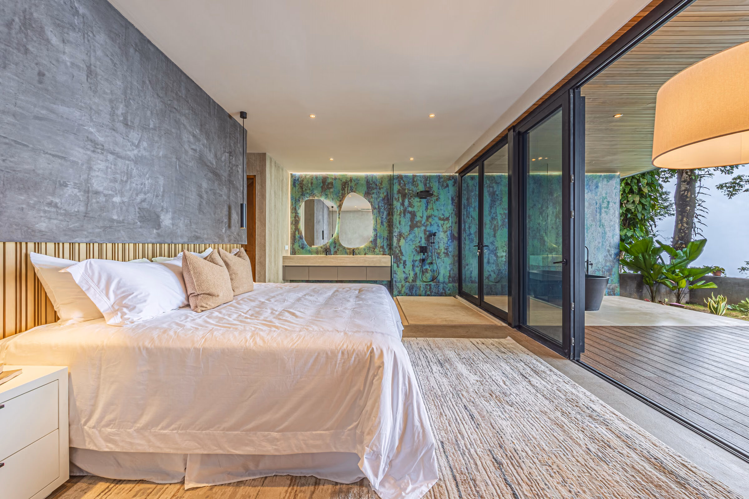 A bedroom opening full-width onto its private deck, bed facing the forest.