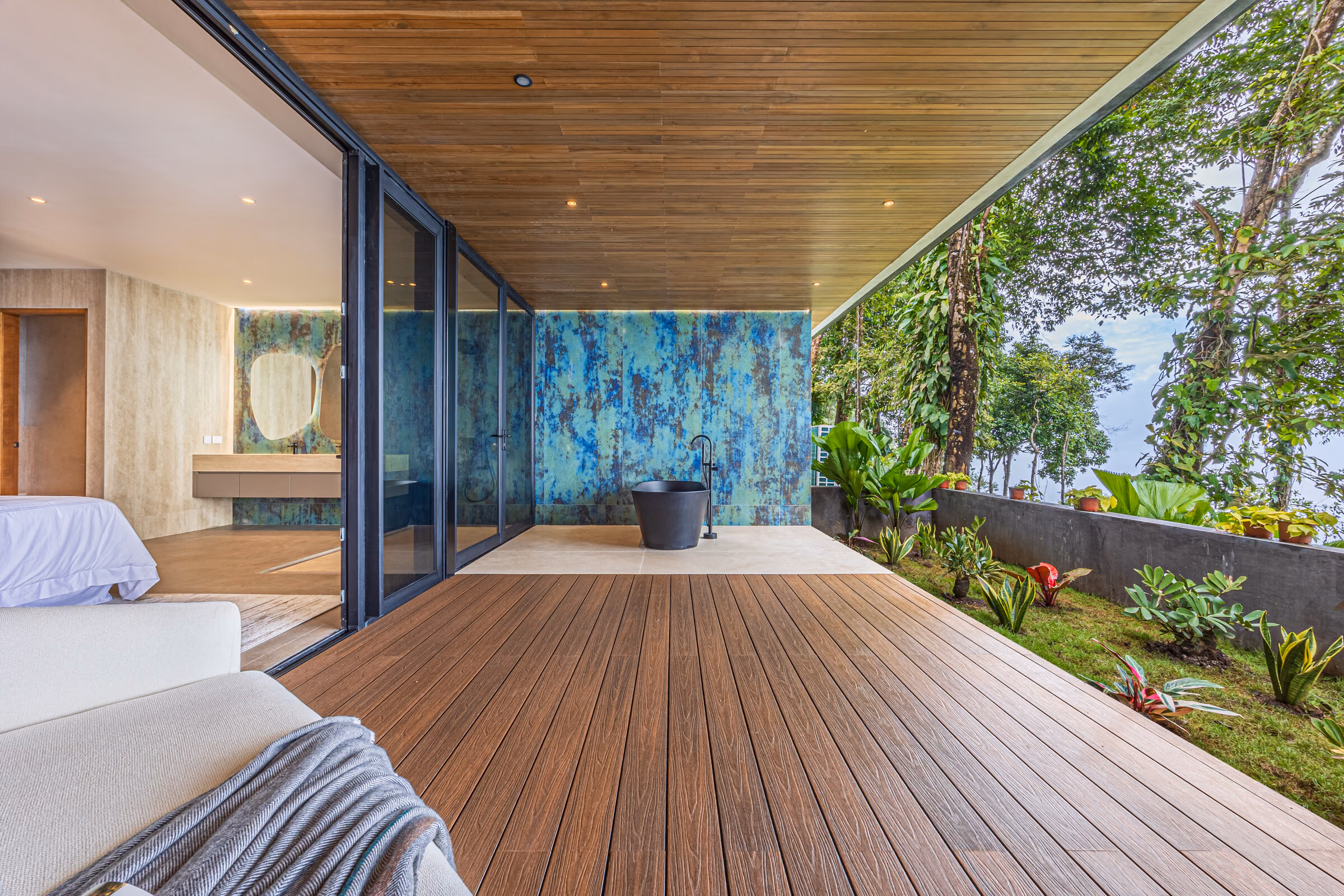 A bedroom opening onto the continuous upper terrace with planting along its edge.