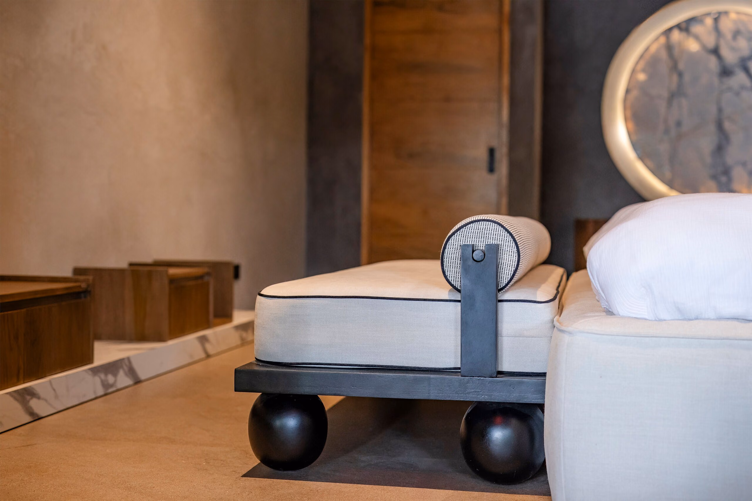 A guest bed set on large dark castors, showing the black wheel and the pale upholstered base.