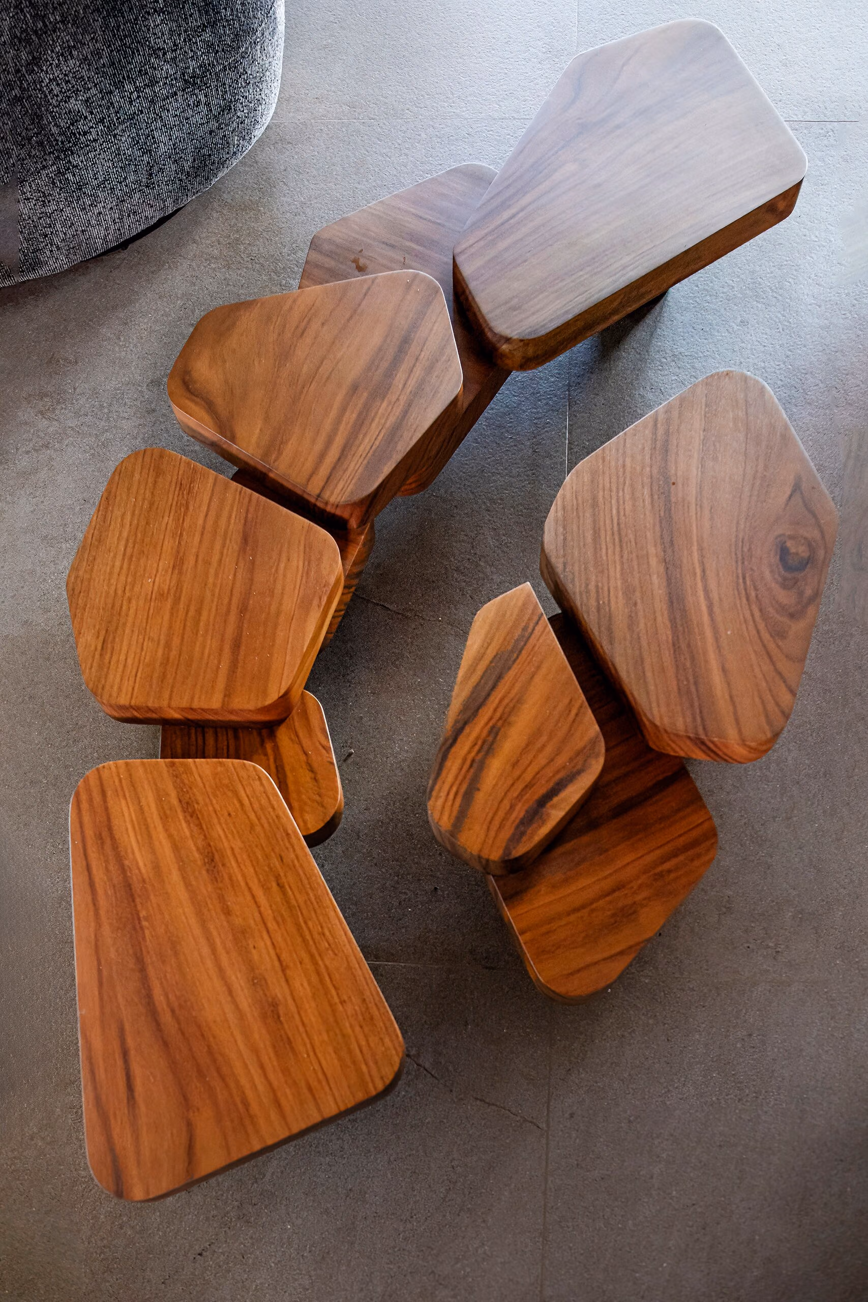 Overhead view of a cluster of sculpted hardwood nesting tables, each cut as an irregular petal-like shape.