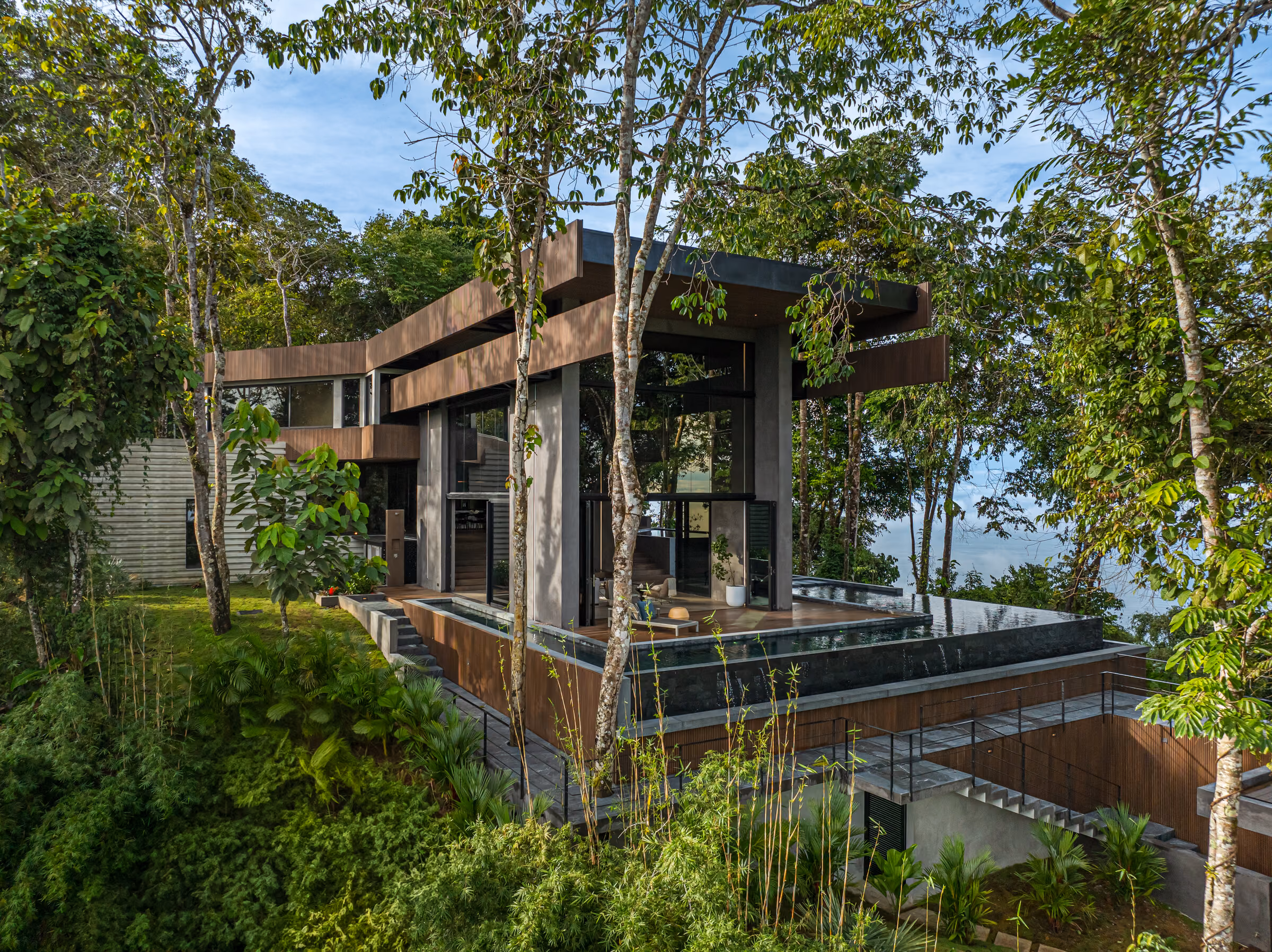 Corazón de Selva seen from below among tall rainforest trees, its horizontal roof lines cutting through the green.